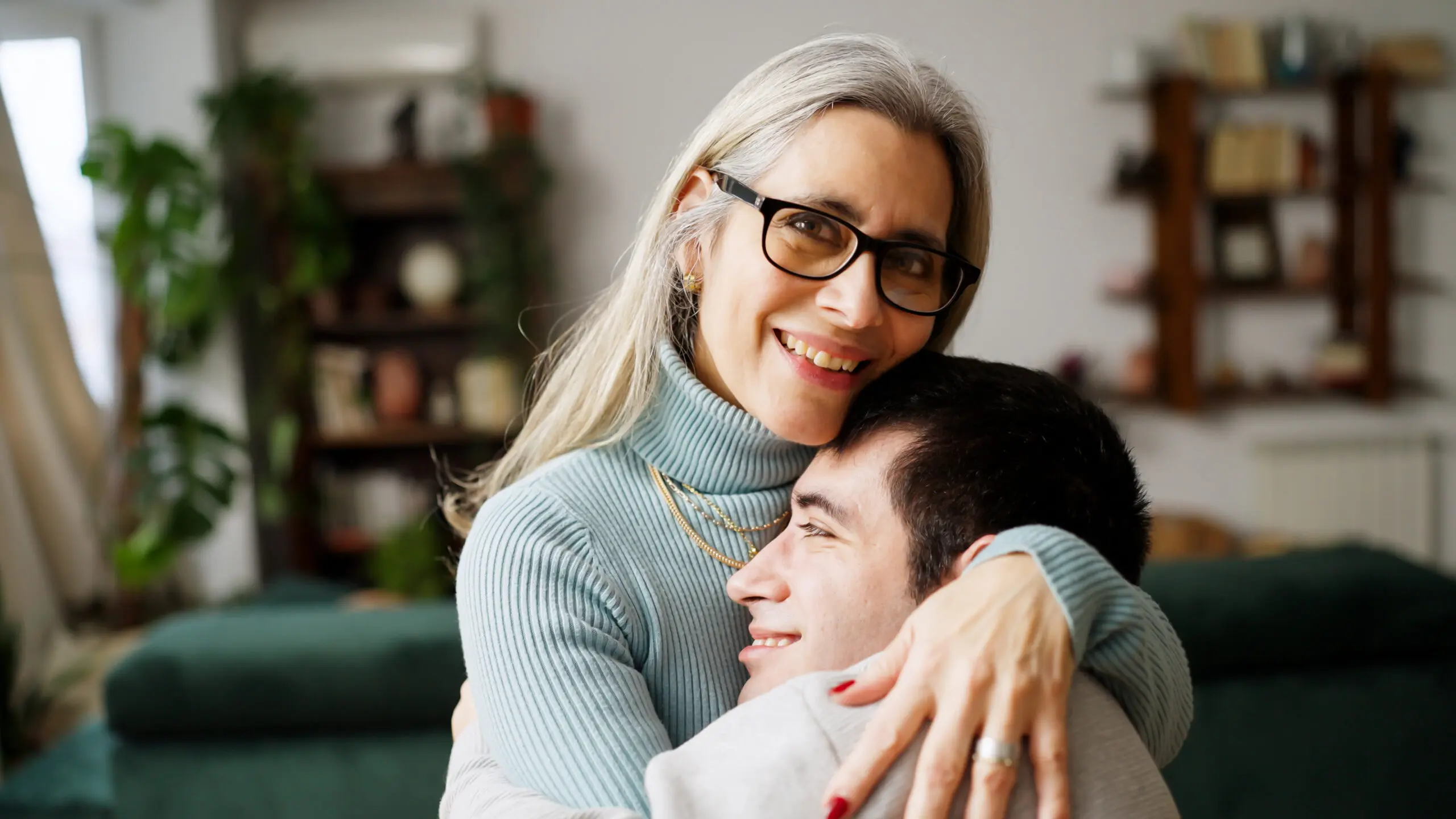A woman embracing a young adult at home