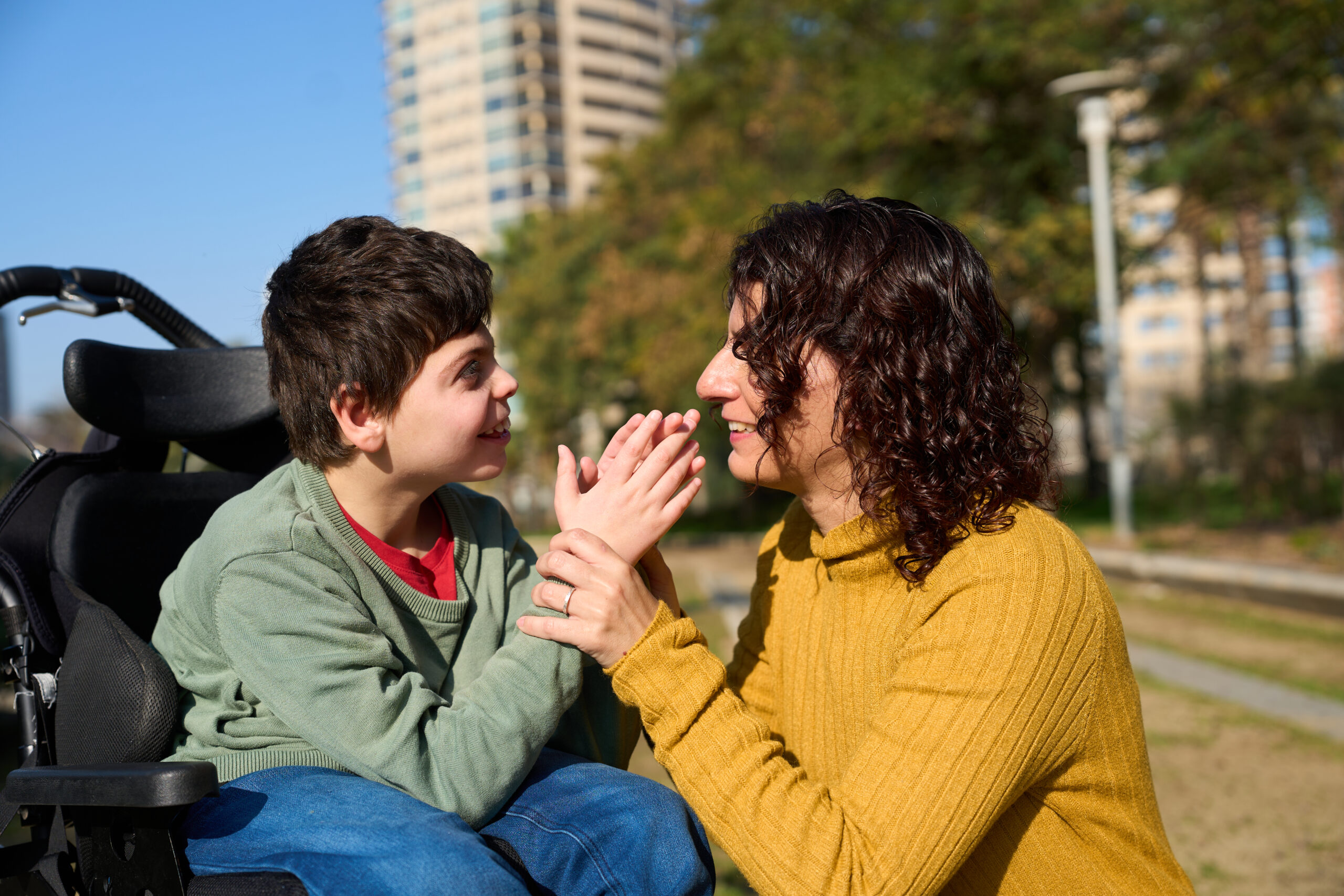 A child using a wheelchair with a caregiver in the park