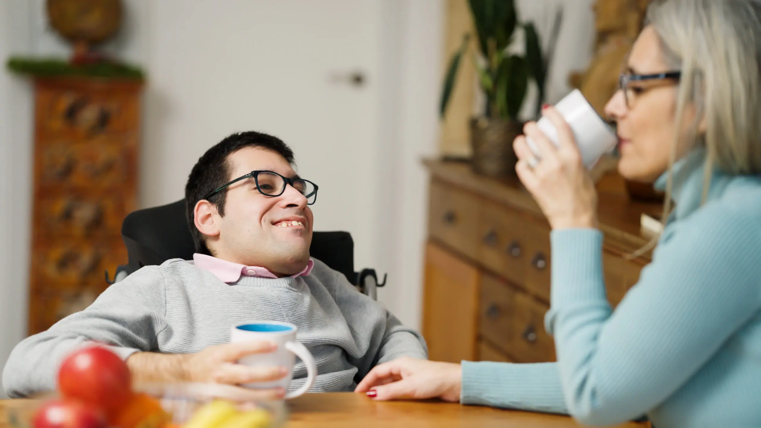 A Direct Support Professional and a person smiling together indoors