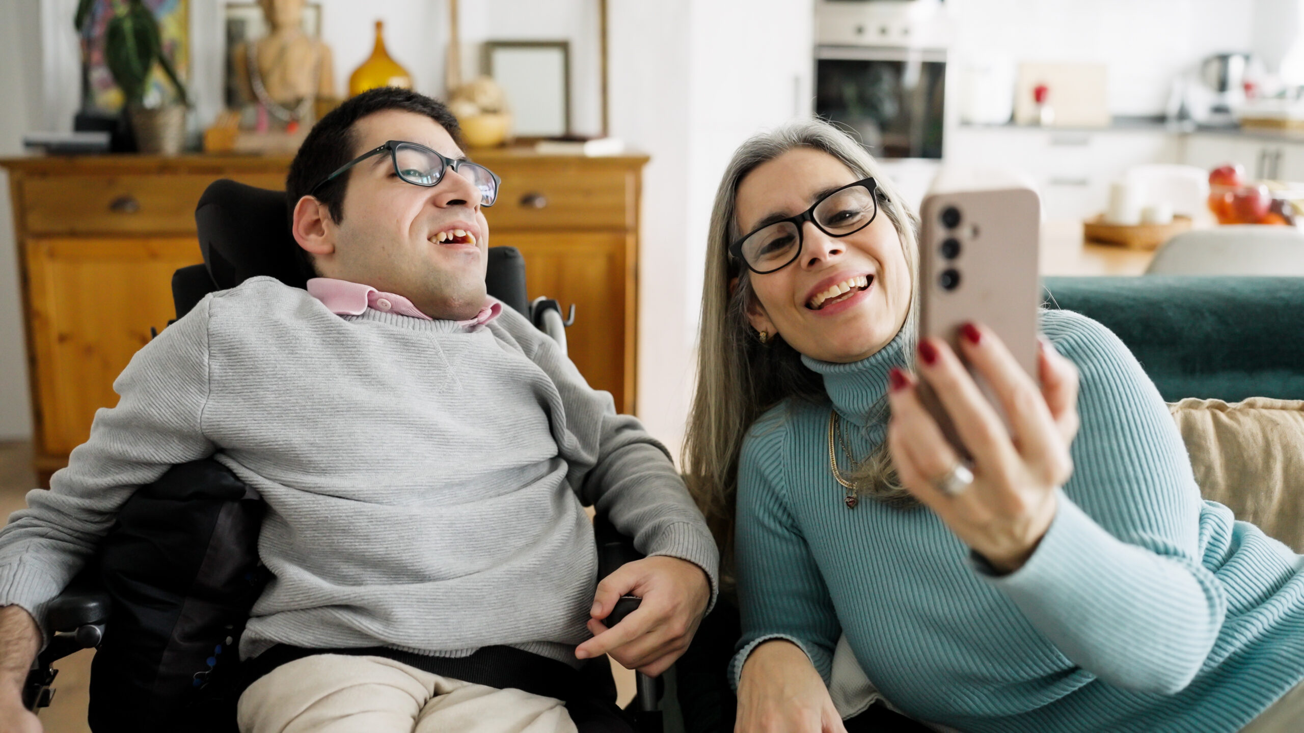 Two people smiling together while taking a selfie indoors.