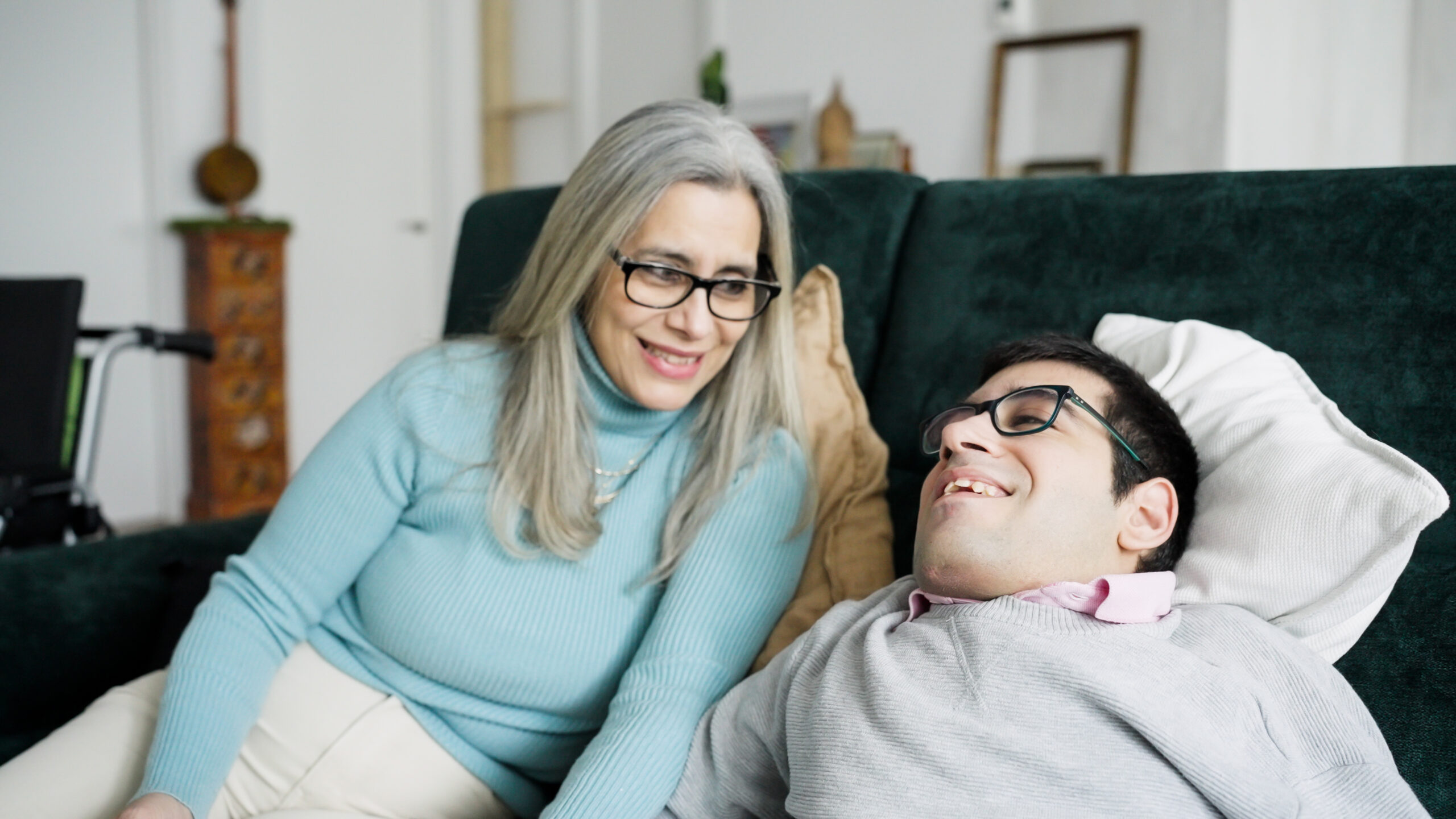 A Direct Support Professional talking with a customer relaxing on a sofa at home
