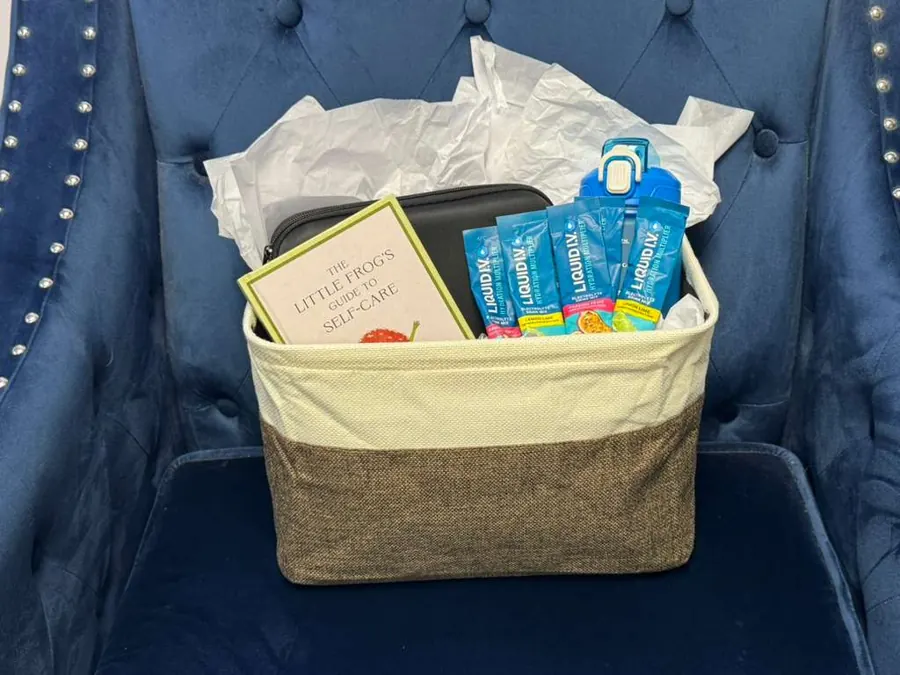 August wellness gift basket with a water bottle, self-care book, heated massage gun, and Liquid I.V.